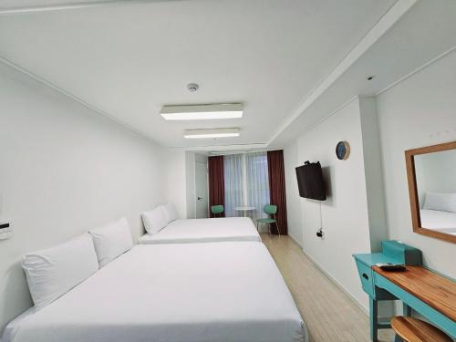 a bedroom with two beds and a table and a mirror at Ciel de Mer in Busan