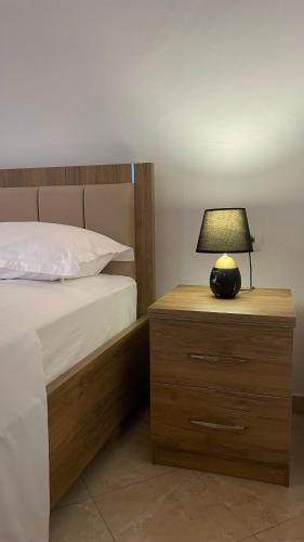 a bed with a night stand with a lamp on it at MEROLI Guesthouse - UNESCO quarter in Berat