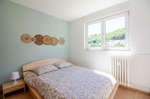 a white bedroom with a bed and two windows at Sweet-Bright in Hayange