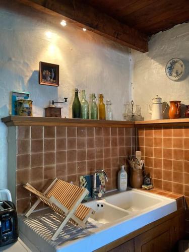 - une cuisine avec un évier et une étagère avec des bouteilles dans l'établissement Gîte de la Placette, à Aumessas