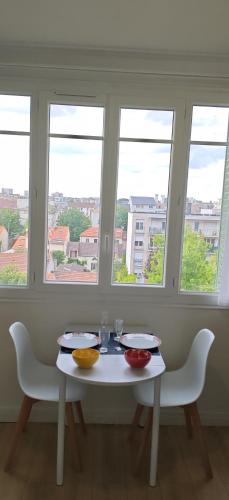 une table blanche avec deux chaises et trois fenêtres dans l'établissement Charmant Studio Cosy Confort, à Alfortville