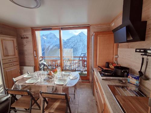 - une cuisine avec une table et une vue sur la montagne dans l'établissement Le belle vue les 2 alpes, à Les Deux Alpes