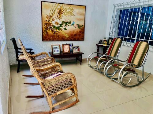 a room with three wicker chairs and a table at Casa Nora Alojamiento Entero, 4 Habitaciones Capacidad Máxima 9 huéspedes in Ríohacha