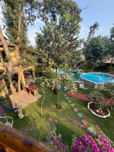 einen Garten mit Pool, Bäumen und Blumen in der Unterkunft Bungalow de 02 pisos en casa de campo El Valle Inn in Cieneguilla