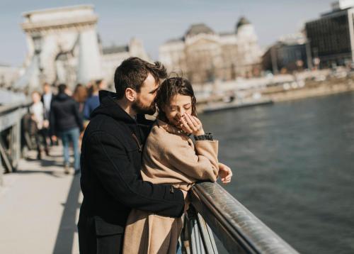 a man and a woman standing on a railing near the water at Verdi Budapest Aquincum in Budapest
