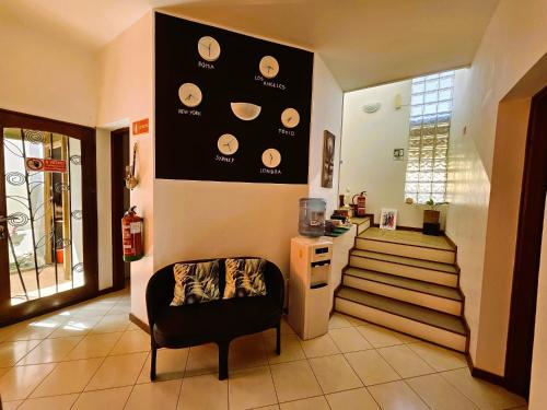 a living room with a chair and a wall with plates at Blue Eagle Guesthouse - Casa de hospedes in Santa Maria