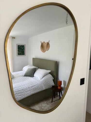 a mirror reflecting a bed in a bedroom at Stylish & central apartment close to the beach in Penzance