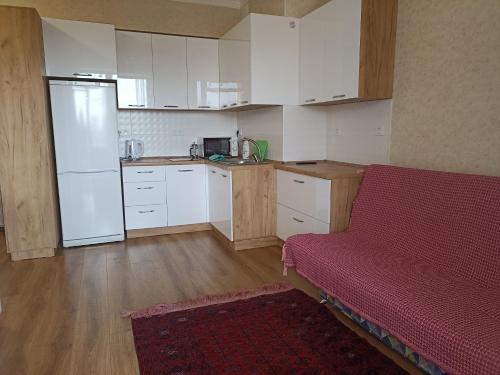 a kitchen with white cabinets and a red couch at квартира в ЦО Радуга Иссык Куль9 Raduga Issyk Kul in Chon-Sary-Oy