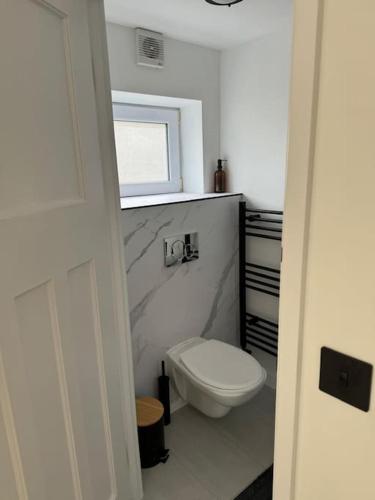 a white bathroom with a toilet and a window at Stylish & central apartment close to the beach in Penzance