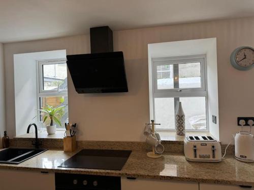 a kitchen with a counter top and two windows at Stylish & central apartment close to the beach in Penzance