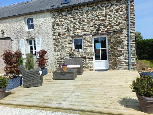 une terrasse en face d'une maison en pierre dans l'établissement Entre terre et mer, à Le Molay-Littry