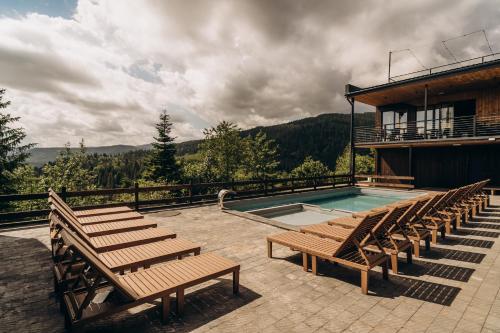 a swimming pool with wooden benches and a building at Mandra Morion in Ogrody