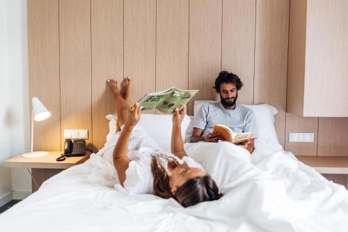 a man and woman laying in bed reading books at Stay Hotel Lisboa Centro Saldanha in Lisbon