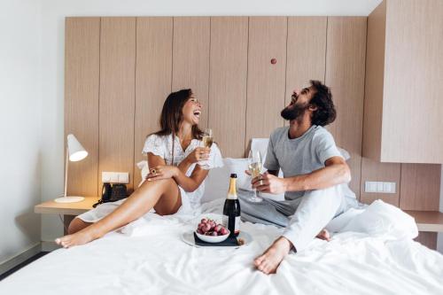 a man and woman sitting on a bed drinking wine at Stay Hotel Lisboa Centro Saldanha in Lisbon