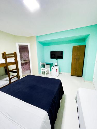 1 dormitorio con paredes azules, 1 cama y TV en Pousada Eu Amo Arraial, en Arraial do Cabo