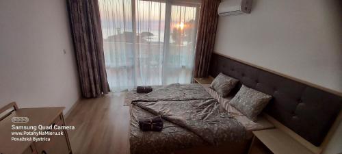 a bedroom with a bed and a large window at SEA WOLF Apartman Луксозен апартамент с панорамна гледка към морето климатик с нова напълно оборудвана кухня отделна баня с тоалетна гледка към басейна на 30 м от плажа Паркинг към хотела Навсякъде близо in Lozenets