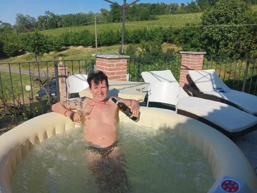 a man holding a glass of wine in a hot tub at La Terrazza del Barbaresco in Neviglie