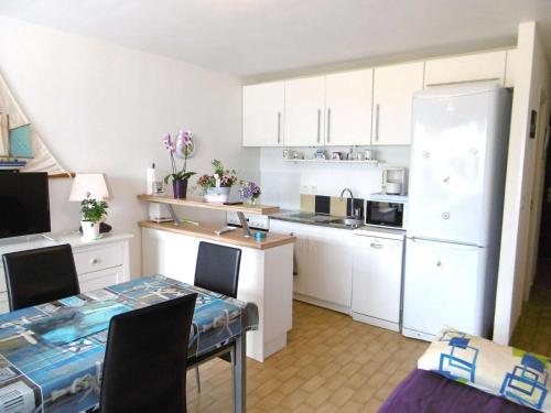 - une cuisine avec des placards blancs, une table et un réfrigérateur dans l'établissement Appartement 2 à 4 personnes - LOMIG, à Sarzeau