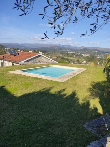 a swimming pool in the middle of a grass field at Casa nos Penedos in Arcos de Valdevez