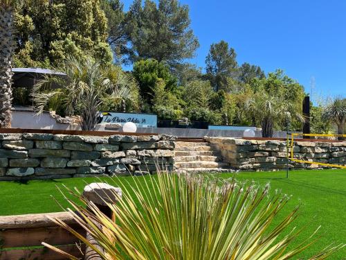 a stone retaining wall in a park with grass at La Pura Vida 34 in Pignan