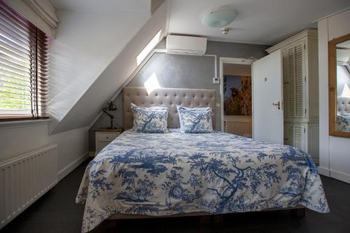 a bedroom with a bed with a blue and white bedspread at Zenzez Hotel & Lounge in Apeldoorn