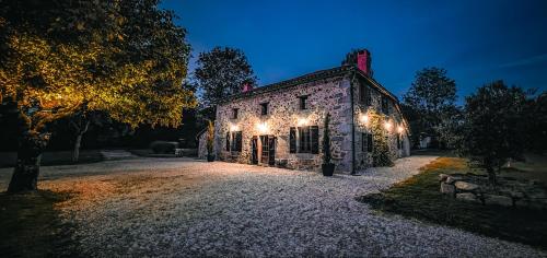 un vieux bâtiment en pierre avec des lumières allumées la nuit dans l'établissement Villa TagiBao avec Piscine chauffée et Spa, à Lesterps