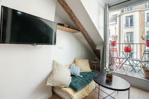 un salon avec une grande télévision à écran plat au mur dans l'établissement Studio luxe au centre des Invalides, à Paris