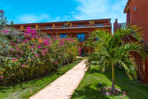 a garden with pink flowers and a building at Royal Horizon Baobab in Somone