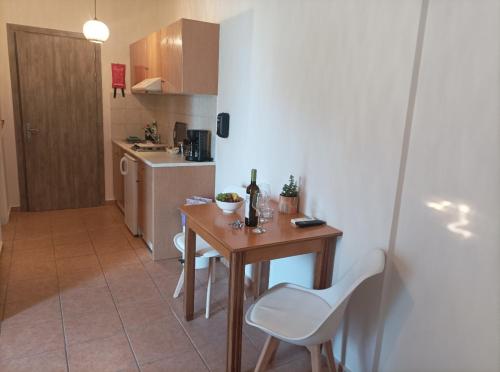a small kitchen with a wooden table and white chairs at Nikolaos Studios Skala in Skala Kefalonias