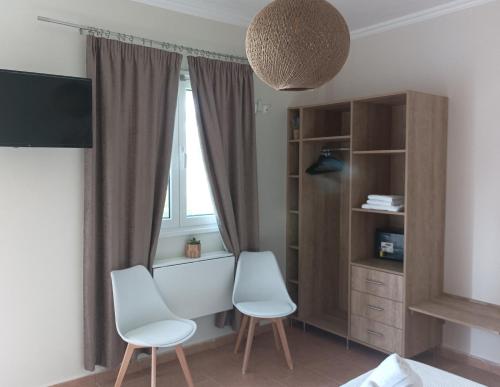 two white chairs in a room with a window at Nikolaos Studios Skala in Skala