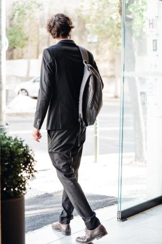a man in a suit with a backpack walking down the street at Stay Hotel Lisboa Centro Saldanha in Lisbon