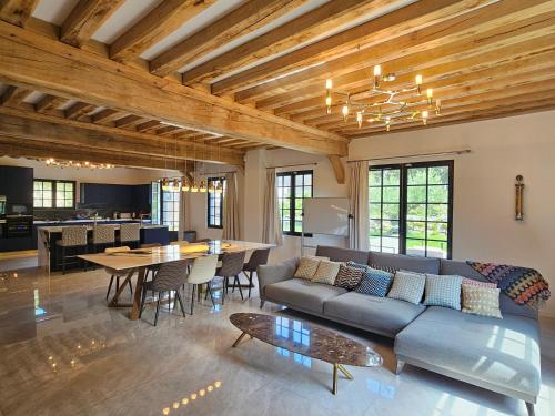 a living room with a couch and a table at Villa d'exception, 5 chambres, 20m plage, spa. in Bénerville-sur-Mer