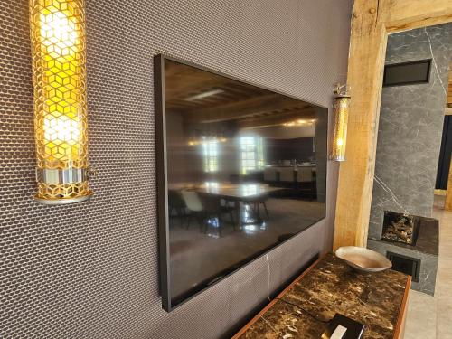 a large television on a wall with a table at Villa d'exception, 5 chambres, 20m plage, spa. in Bénerville-sur-Mer