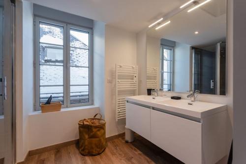 une salle de bain blanche avec un lavabo et un miroir dans l'établissement Appartement de charme pour 5P, à Cauterets