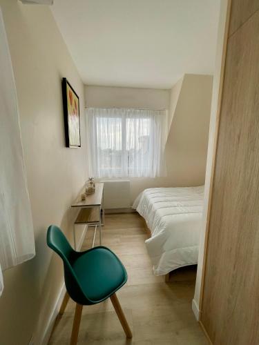 - une chambre avec une chaise verte et un lit dans l'établissement Appartement bord de mer Houlgate, à Houlgate