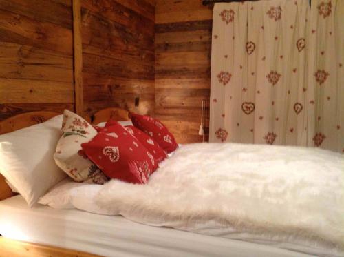 a bed with red and white pillows on it at Chalet Alouette in Grimentz