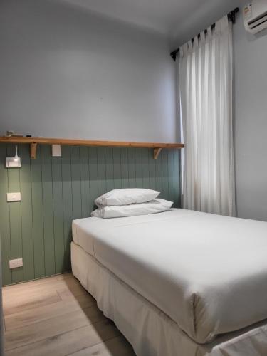 a bedroom with a white bed and a green wall at Hotel Las Terrazas Express in Chillán