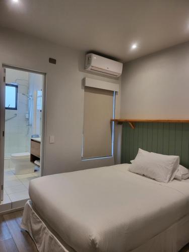 a bedroom with a large white bed and a bathroom at Hotel Las Terrazas Express in Chillán