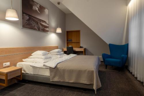 a hotel room with a bed and a blue chair at Hotel Salve in Głogówek