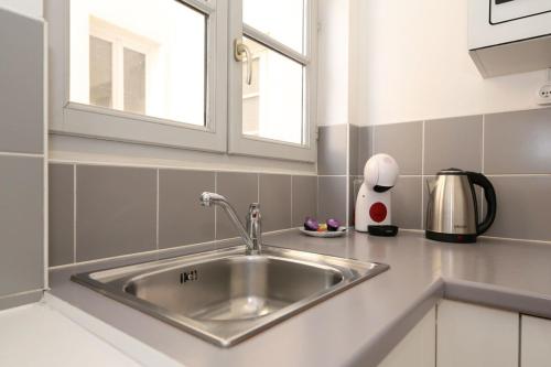 un évier en acier inoxydable dans une cuisine avec une fenêtre dans l'établissement 202 - Studio calme et reposant a Paris 5 - FLAT-GUEST, à Paris
