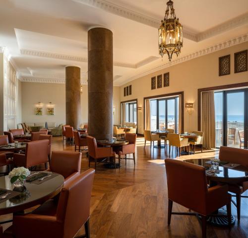 a restaurant with tables and chairs and a chandelier at Sofitel Bahrain Zallaq Thalassa Sea & Spa in Manama