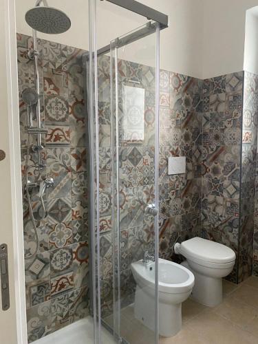 a bathroom with a toilet and a glass shower stall at Salenzia apartment in San Cesario di Lecce