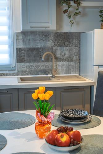 a kitchen with a table with a vase of flowers and fruit at Oázis Tapolca Apartman in Miskolctapolca