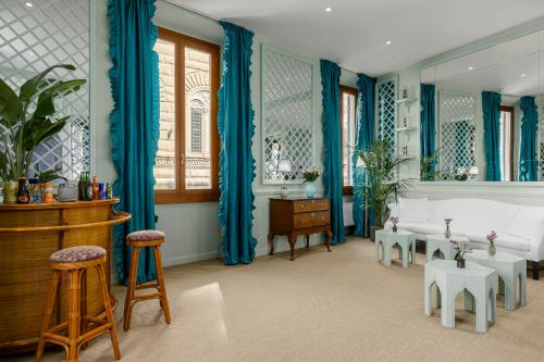 a living room with blue curtains and a couch and stool at Room Mate Collection Isabella, Florence in Florence
