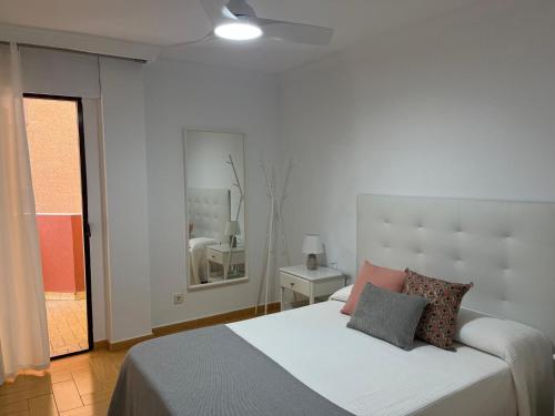 una camera bianca con un letto con cuscini sopra di El Yate Paseo Marítimo Puerto Deportivo a Fuengirola