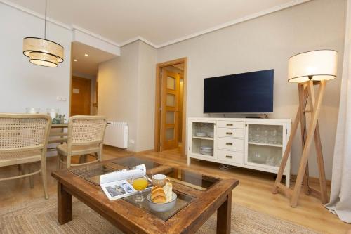 Una sala de estar con una mesa y un televisor. en El Roble by BeValle, en El Pueyo de Jaca