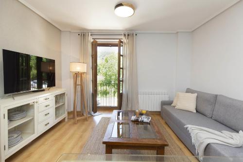 Una sala de estar con un sofá y un televisor. en El Roble by BeValle, en El Pueyo de Jaca