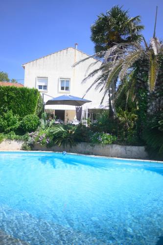 une grande piscine bleue devant une maison dans l'établissement Chambres d'Hôtes Béziers, à Béziers