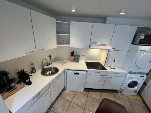 a small kitchen with white cabinets and a sink at Appartement Lijnden in Lijnden
