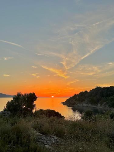 a sunset over a body of water with the sun setting at Iris Sunset View Home in Samos